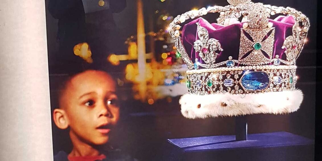 Cropped photo of a billboard at St Pancras in 2019 showing a black boy gazing longingly at the crown jewels