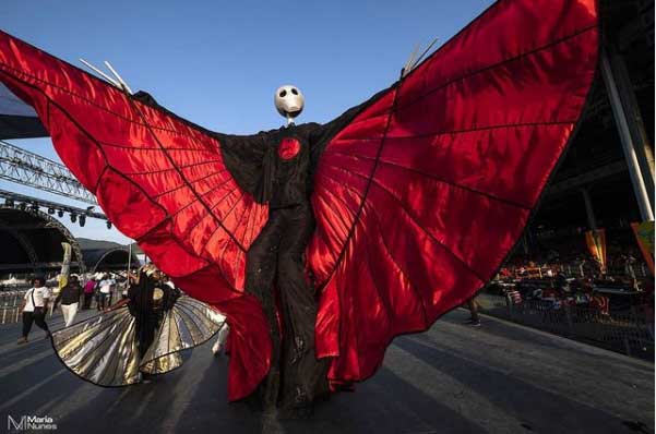 stilt walker costume with giant red wings and a skull for head