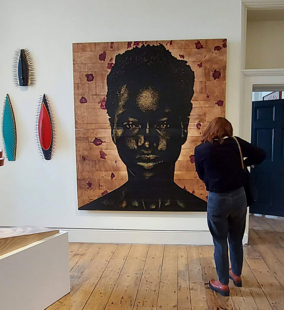 portrait of a young Black girl using silver tipped black nails on wooden planks